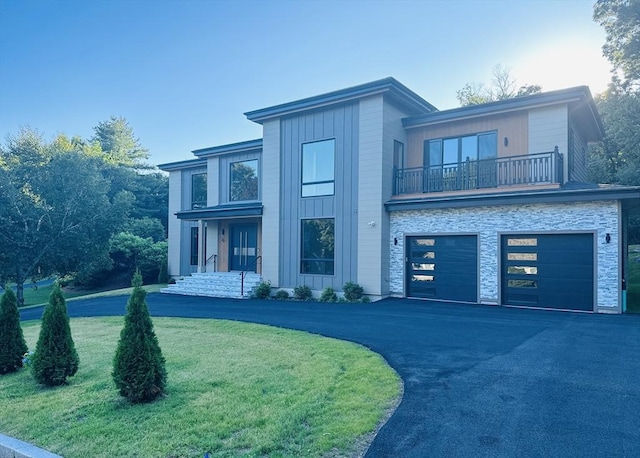 view of front of home featuring a balcony, a front yard, and a garage