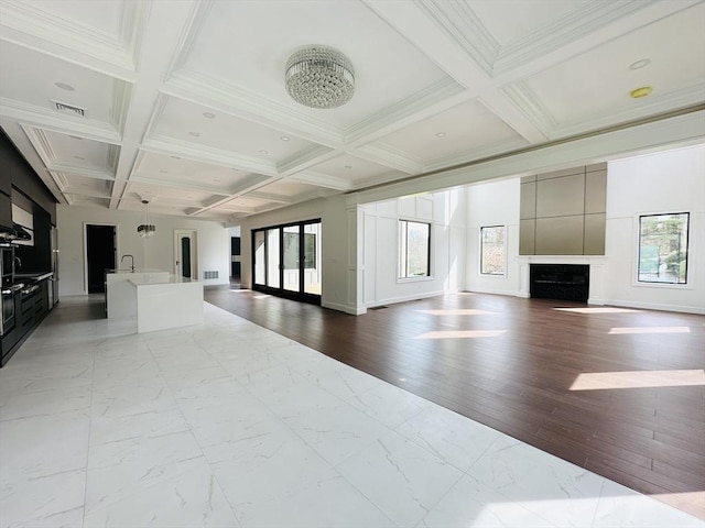 unfurnished living room with beam ceiling, a wealth of natural light, and coffered ceiling