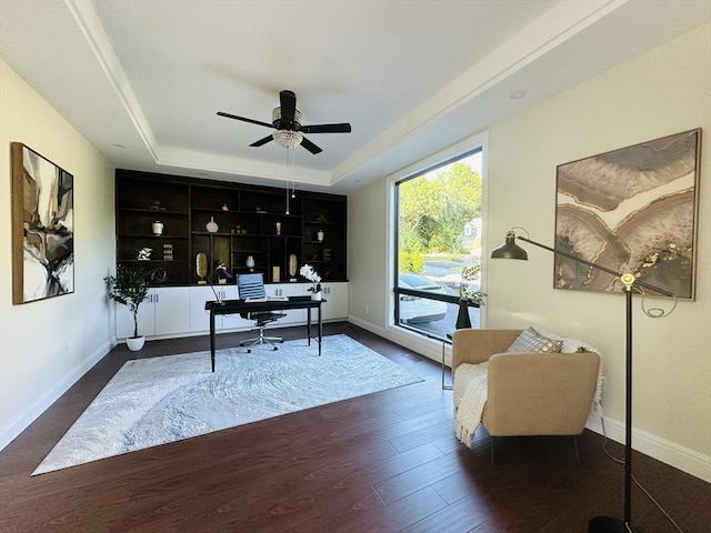 home office featuring a tray ceiling, dark hardwood / wood-style floors, and ceiling fan