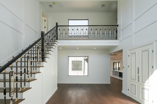 stairway with wood-type flooring and a high ceiling