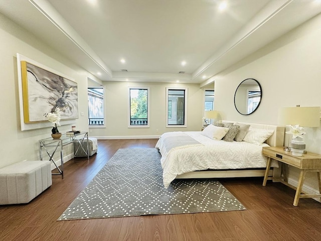 bedroom with a raised ceiling and dark hardwood / wood-style floors