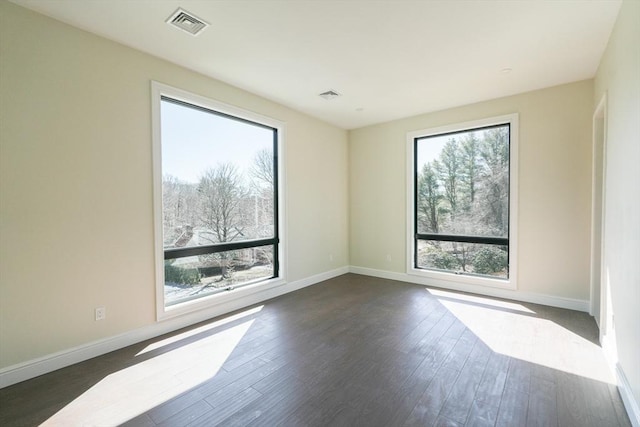 empty room with dark hardwood / wood-style floors and a healthy amount of sunlight