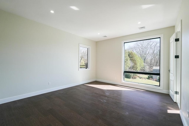 empty room with dark hardwood / wood-style flooring and a healthy amount of sunlight