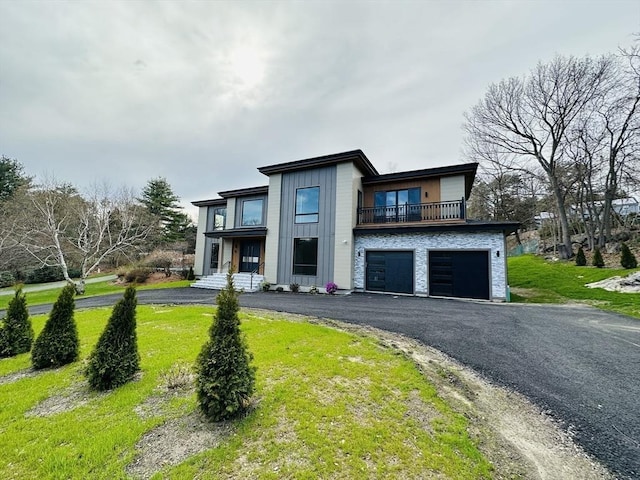 modern home featuring a front yard, a balcony, and a garage