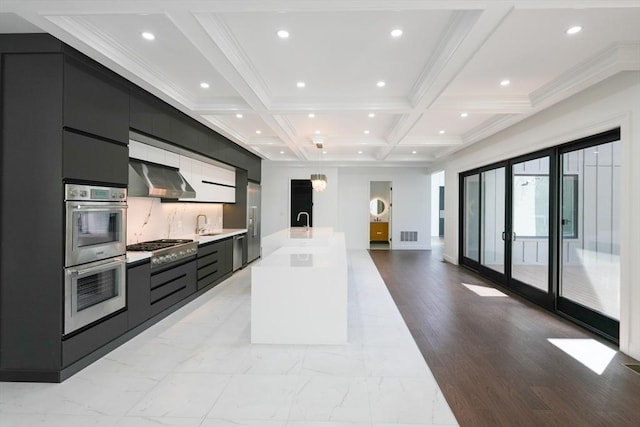 kitchen featuring coffered ceiling, wall chimney exhaust hood, beamed ceiling, a large island, and stainless steel appliances