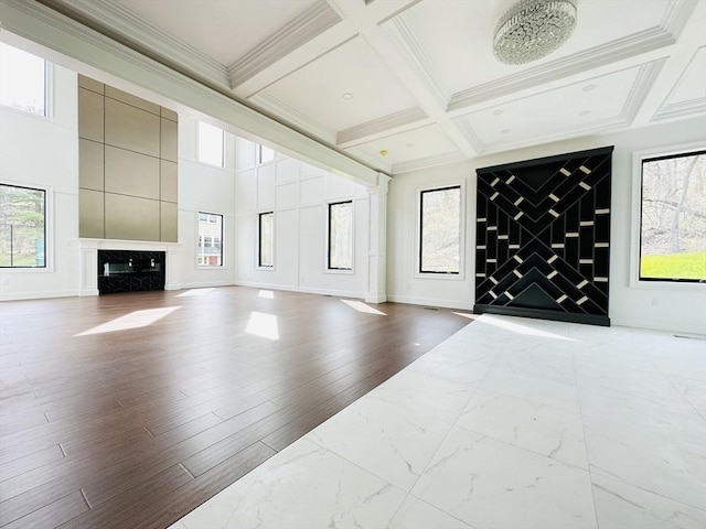 living room featuring beam ceiling, a healthy amount of sunlight, coffered ceiling, and ornamental molding