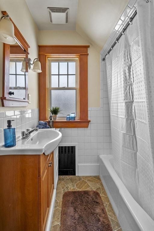 bathroom featuring lofted ceiling, tile walls, shower / tub combo, radiator heating unit, and vanity