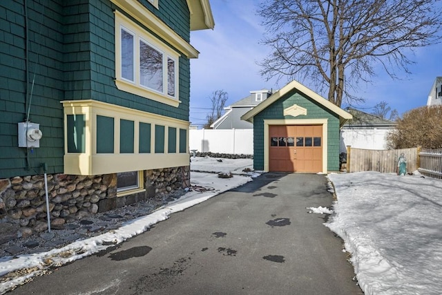 view of snowy exterior featuring a garage and an outdoor structure