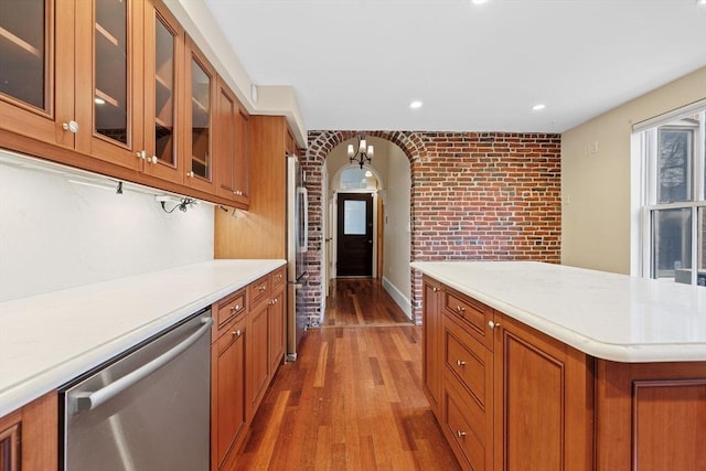 31 Millmont St Unit 1, Boston, MA 02119 - kitchen with brown cabinetry, brick wall, wood finished floors, dishwasher, and light countertops