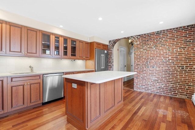 31 Millmont St Unit 1, Boston, MA 02119 - kitchen featuring a sink, wood finished floors, brick wall, and stainless steel appliances