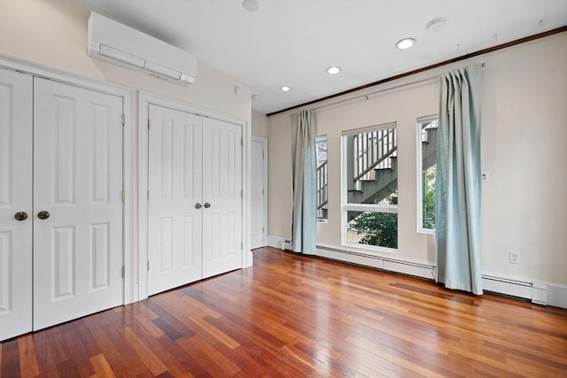 31 Millmont St Unit 1, Boston, MA 02119 - unfurnished bedroom featuring two closets, recessed lighting, a wall unit AC, wood finished floors, and a baseboard heating unit