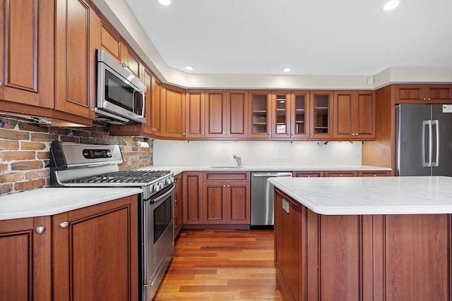 31 Millmont St Unit 1, Boston, MA 02119 - kitchen featuring a sink, appliances with stainless steel finishes, brown cabinets, and light wood-type flooring