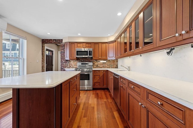 31 Millmont St Unit 1, Boston, MA 02119 - kitchen featuring light countertops, brown cabinets, hardwood / wood-style flooring, appliances with stainless steel finishes, and backsplash