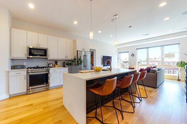488 Dorchester Ave Unit 4H, Boston, MA 02127 - kitchen featuring appliances with stainless steel finishes, light wood-style flooring, light countertops, tasteful backsplash, and a breakfast bar