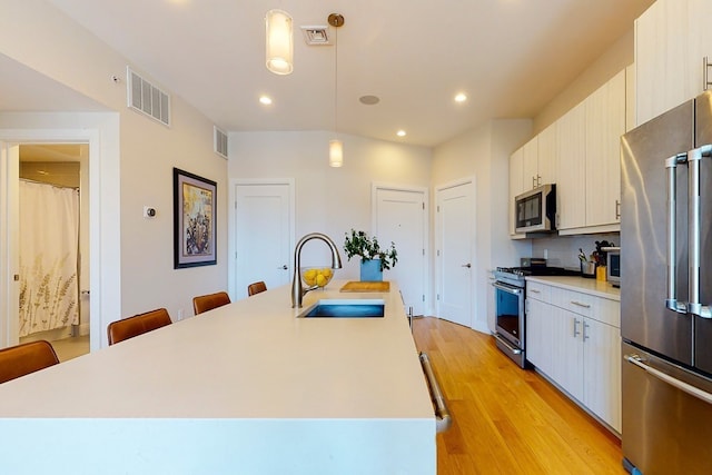 488 Dorchester Ave Unit 4H, Boston, MA 02127 - kitchen featuring stainless steel appliances, a kitchen bar, a sink, hanging light fixtures, and light countertops