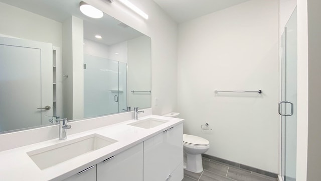 bathroom featuring a shower with door, toilet, and vanity