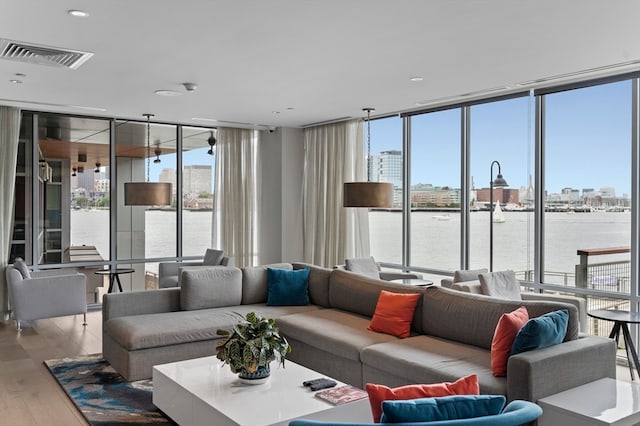 living room featuring a wall of windows, hardwood / wood-style floors, and a water view