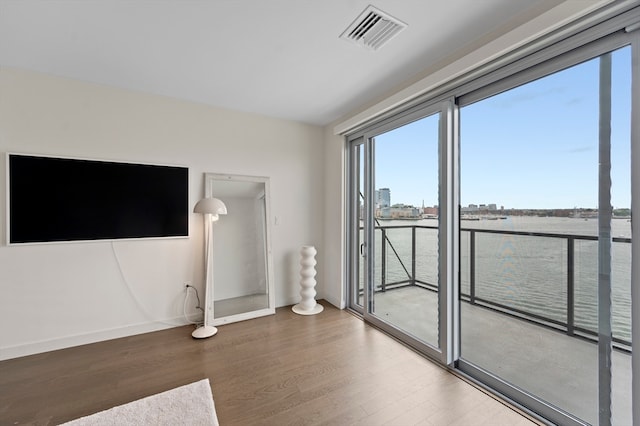 unfurnished living room featuring hardwood / wood-style floors and a water view