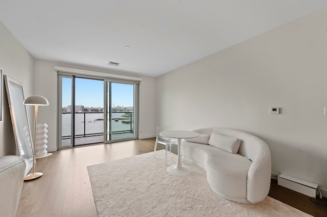 living room featuring a baseboard heating unit, a water view, and wood-type flooring