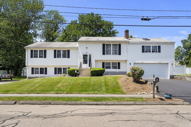 35 Pilgrim Dr, Norwood, MA 02062 - bi-level home with asphalt driveway, an attached garage, a front lawn, and a chimney