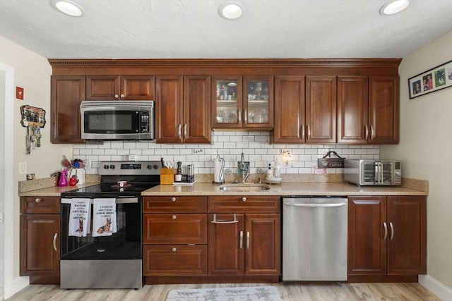 35 Pilgrim Dr, Norwood, MA 02062 - kitchen featuring stainless steel appliances, light wood-style floors, decorative backsplash, glass insert cabinets, and recessed lighting