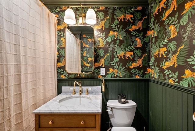 full bath with wainscoting, wallpapered walls, vanity, and toilet