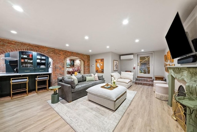 living area with a wall mounted air conditioner, light wood-style floors, and brick wall