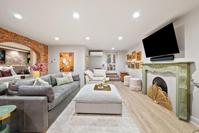 living room with wood finished floors, brick wall, a premium fireplace, recessed lighting, and a wall mounted air conditioner