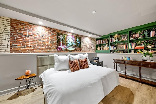 bedroom with brick wall, baseboards, and wood finished floors