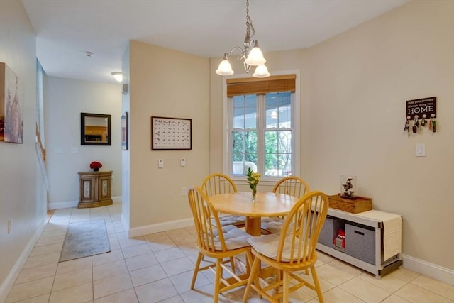 dining area featuring light tile patterned flooring, a chandelier, and baseboards