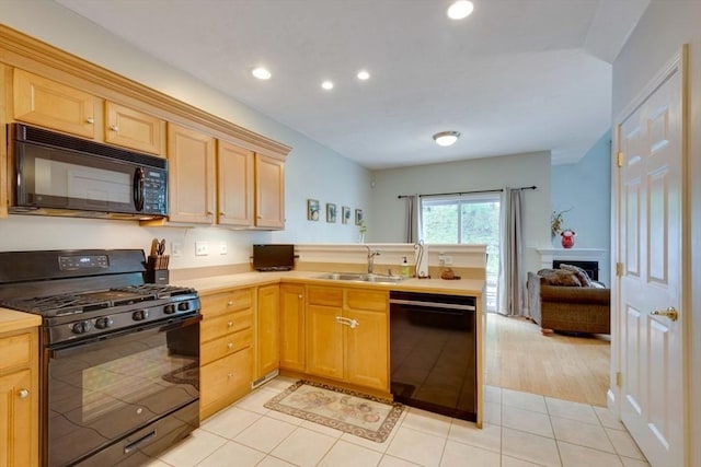 kitchen with black appliances, a sink, a peninsula, light countertops, and light brown cabinetry