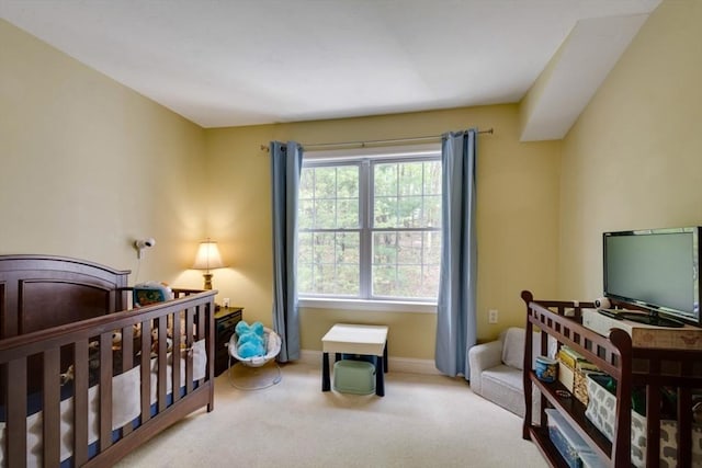 carpeted bedroom with baseboards and a crib