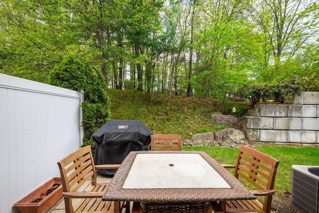 deck with outdoor dining space, central AC unit, and grilling area