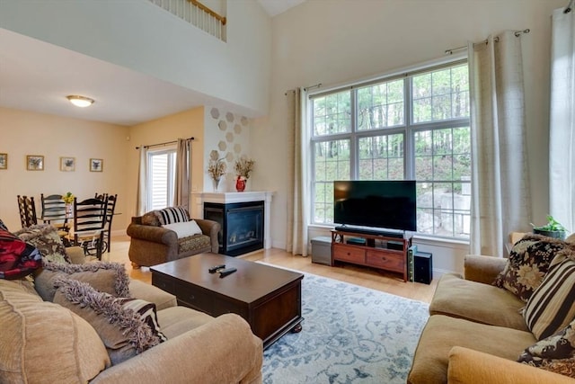 living room featuring a glass covered fireplace, light wood-style floors, and baseboards