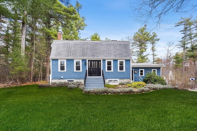 colonial inspired home with a shingled roof, a chimney, and a front yard