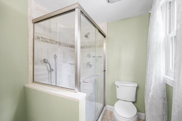 bathroom with a shower stall, toilet, and tile patterned floors