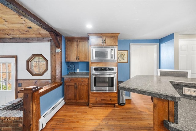kitchen featuring a breakfast bar area, light wood-style flooring, appliances with stainless steel finishes, brown cabinets, and a baseboard radiator
