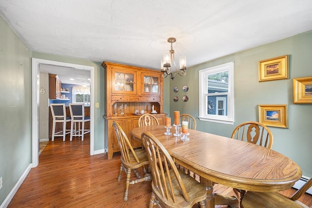 dining room featuring wood finished floors, baseboards, a notable chandelier, and plenty of natural light