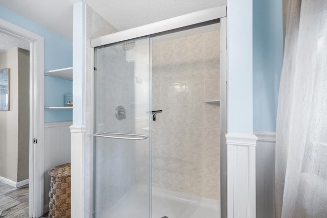 full bathroom featuring a shower stall and wainscoting