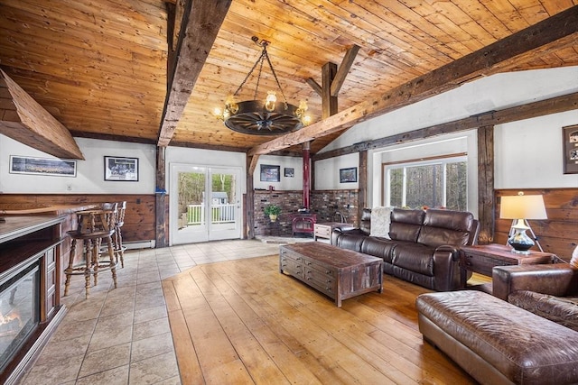 living room featuring a chandelier, a wood stove, wood ceiling, and a healthy amount of sunlight