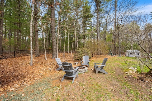 view of yard with an outdoor structure, a fire pit, a storage shed, and fence