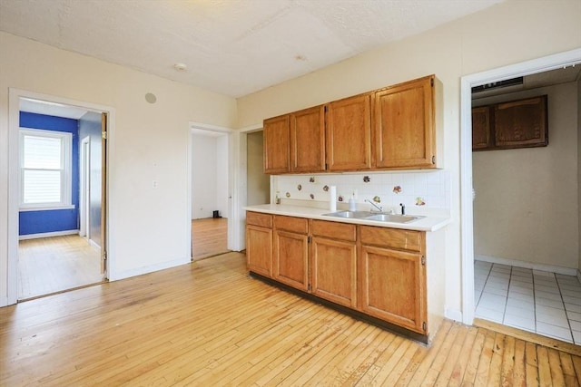 37 Colton St, Worcester, MA 01610 - kitchen with light countertops, light wood-style floors, tasteful backsplash, and brown cabinets