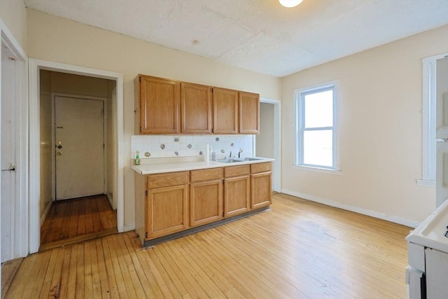 37 Colton St, Worcester, MA 01610 - kitchen featuring light countertops, light wood-style flooring, backsplash, brown cabinets, and a textured ceiling