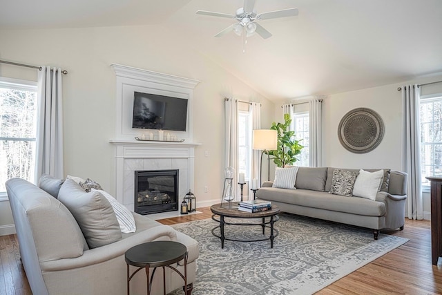 living room featuring lofted ceiling, hardwood / wood-style floors, ceiling fan, and a fireplace