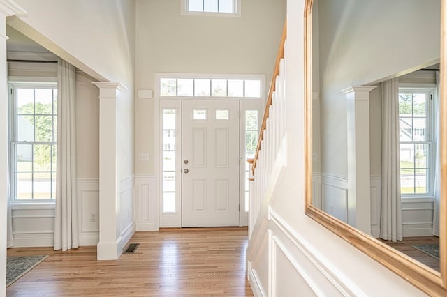 entryway featuring decorative columns, a healthy amount of sunlight, and light wood-type flooring