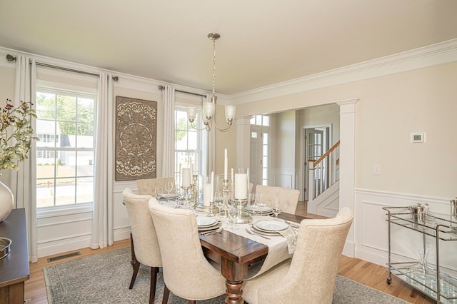 dining space with an inviting chandelier, light hardwood / wood-style flooring, ornamental molding, and a healthy amount of sunlight