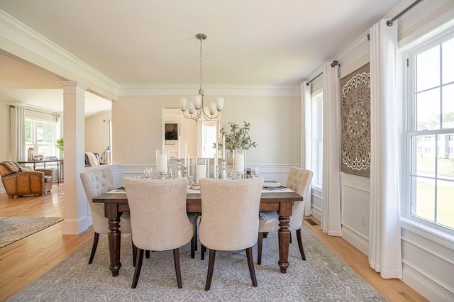 dining area with a chandelier, a healthy amount of sunlight, decorative columns, and light hardwood / wood-style flooring