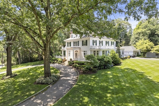 view of front of property with covered porch, driveway, a chimney, and a front lawn