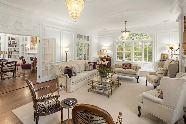 living area with a fireplace, ornamental molding, a decorative wall, and wood finished floors