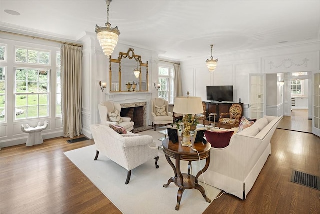 living room featuring a premium fireplace, ornamental molding, a decorative wall, and wood finished floors